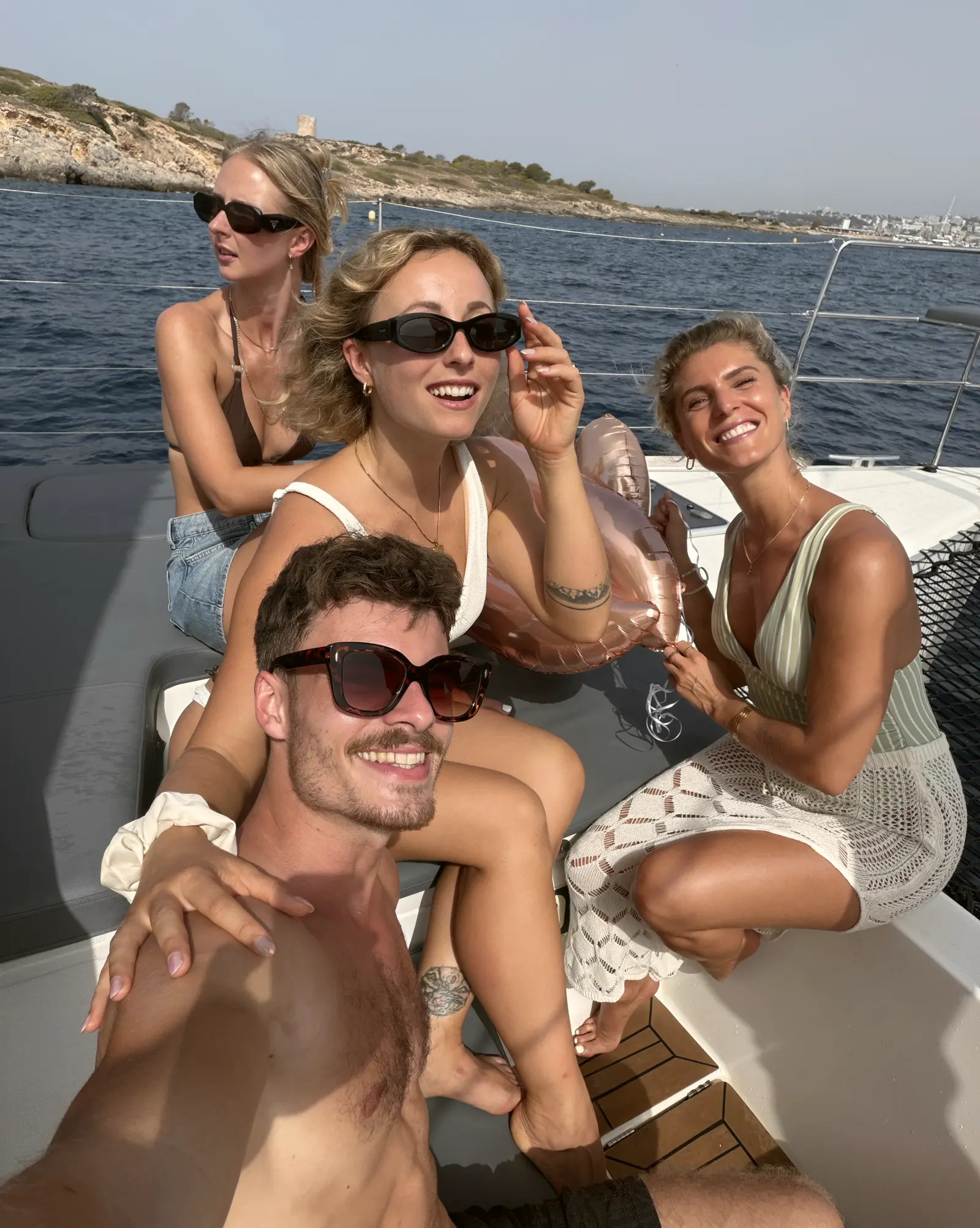 Vier Freunde mit Sonnenbrillen und Ballon auf einem Boot