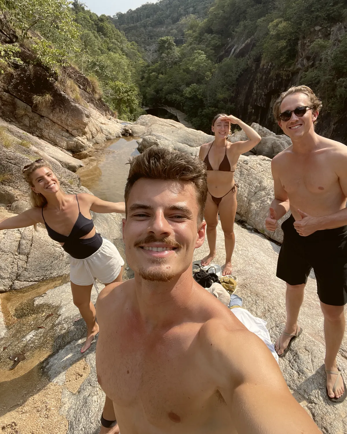 Vier Menschen an einem Wasserfall im Dschungel, lachend